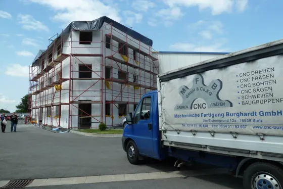 Rohbau des Bürogebäudes, davor ein MFB-Transporter